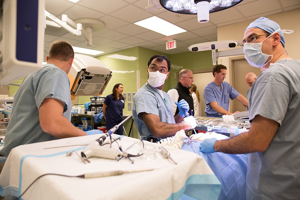 people in scrubs and masks training in surgical simulation environment